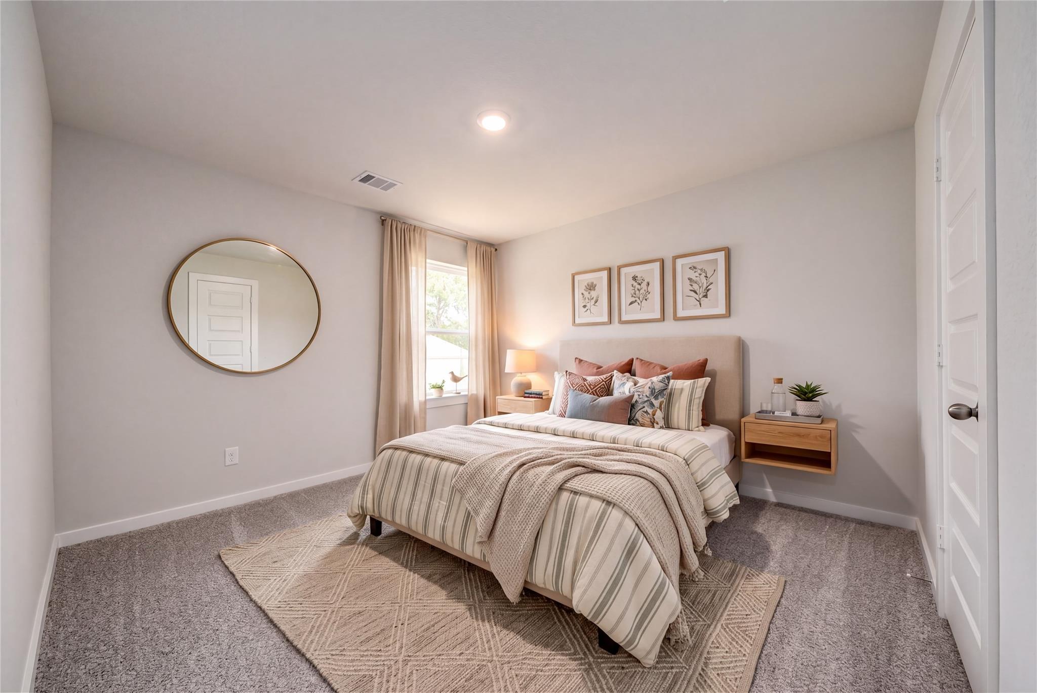 Cozy bedroom with neutral decor and patterned bedding in The Sabine E floor plan at Windmill Estates, Magnolia, Texas.