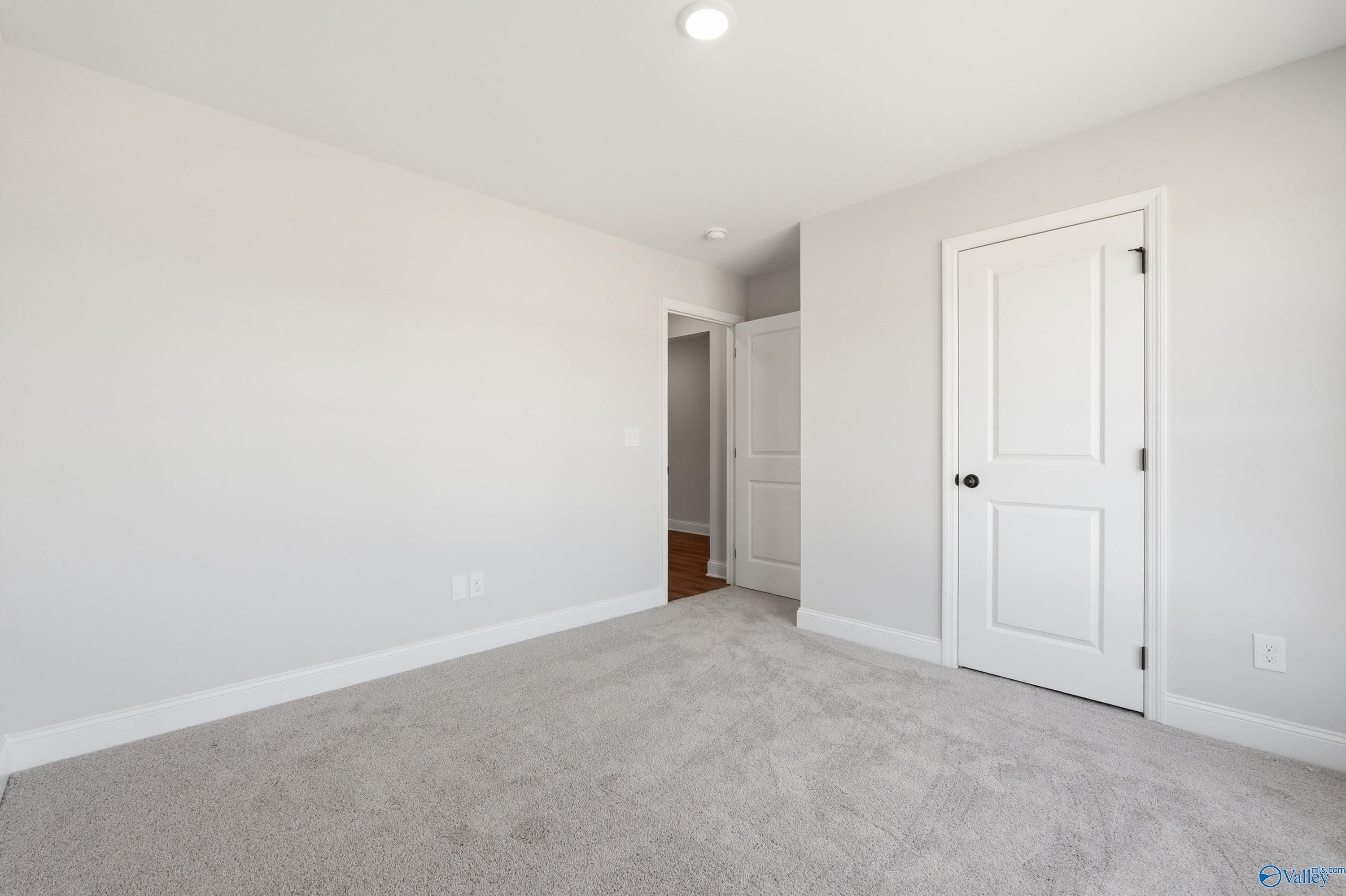 Bright secondary bedroom with gray walls, white doors, and carpet flooring in Davidson Homes The Franklin V, Athens, Alabama