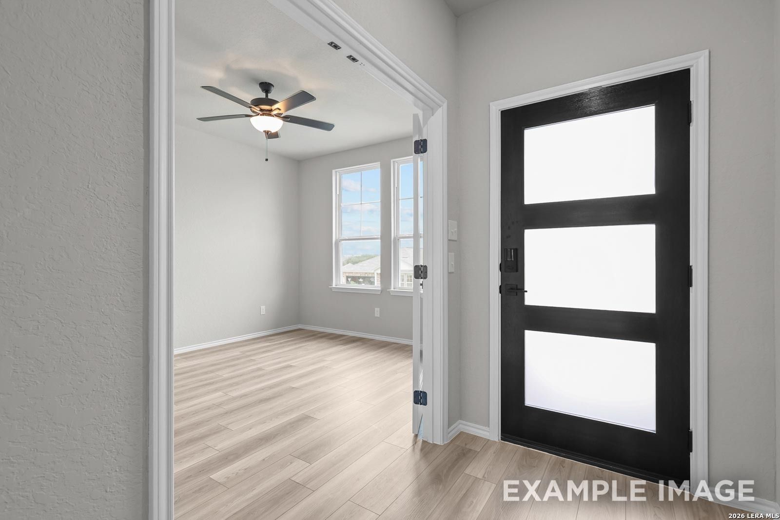 Bright study with ceiling fan and wood-look flooring off the entryway of The Glenwood E home in Royal Crest, San Antonio.