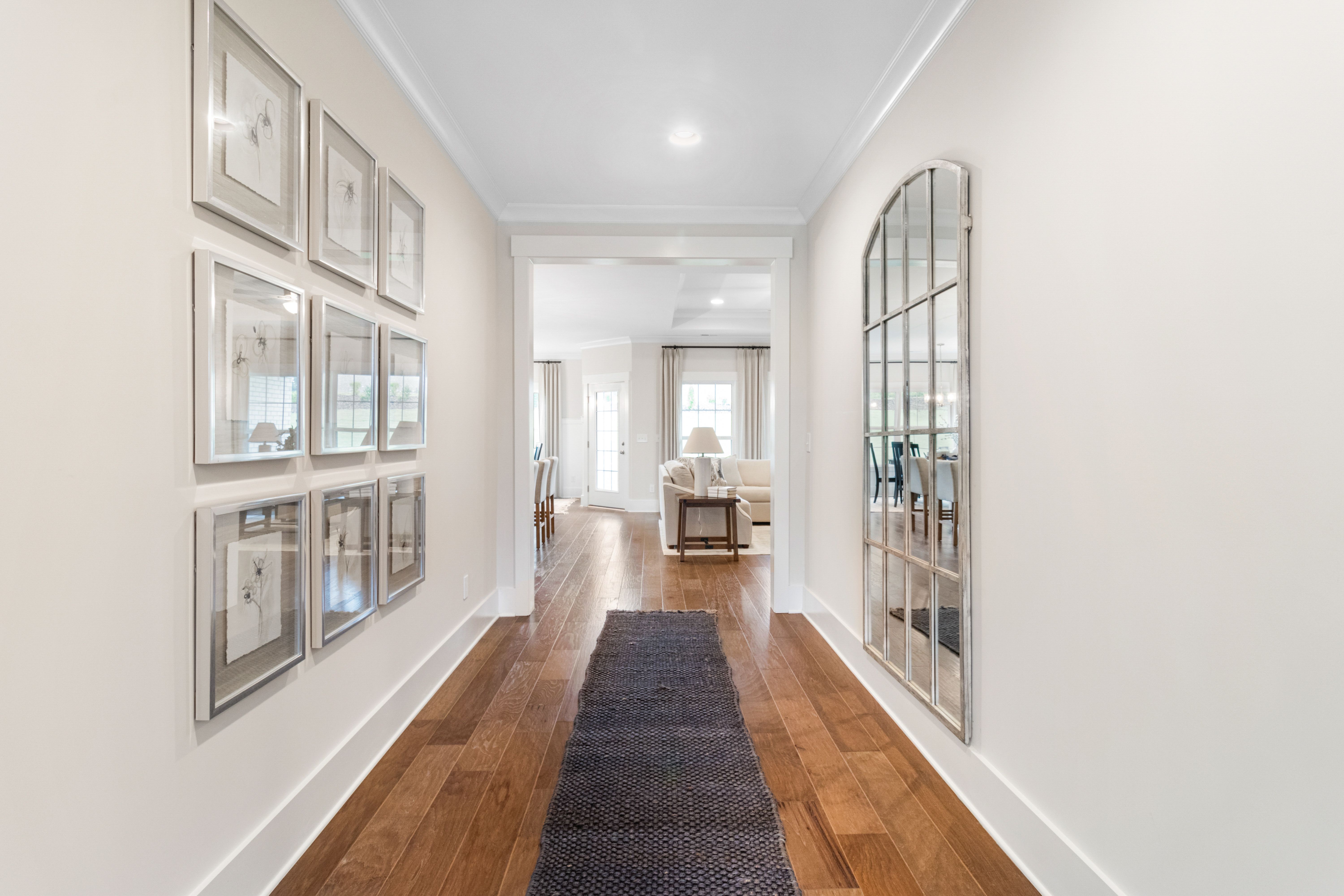 Elegant foyer hallway in Noble Ridge Cullman AL home by Davidson Homes with hardwood floors arched mirror and framed art
