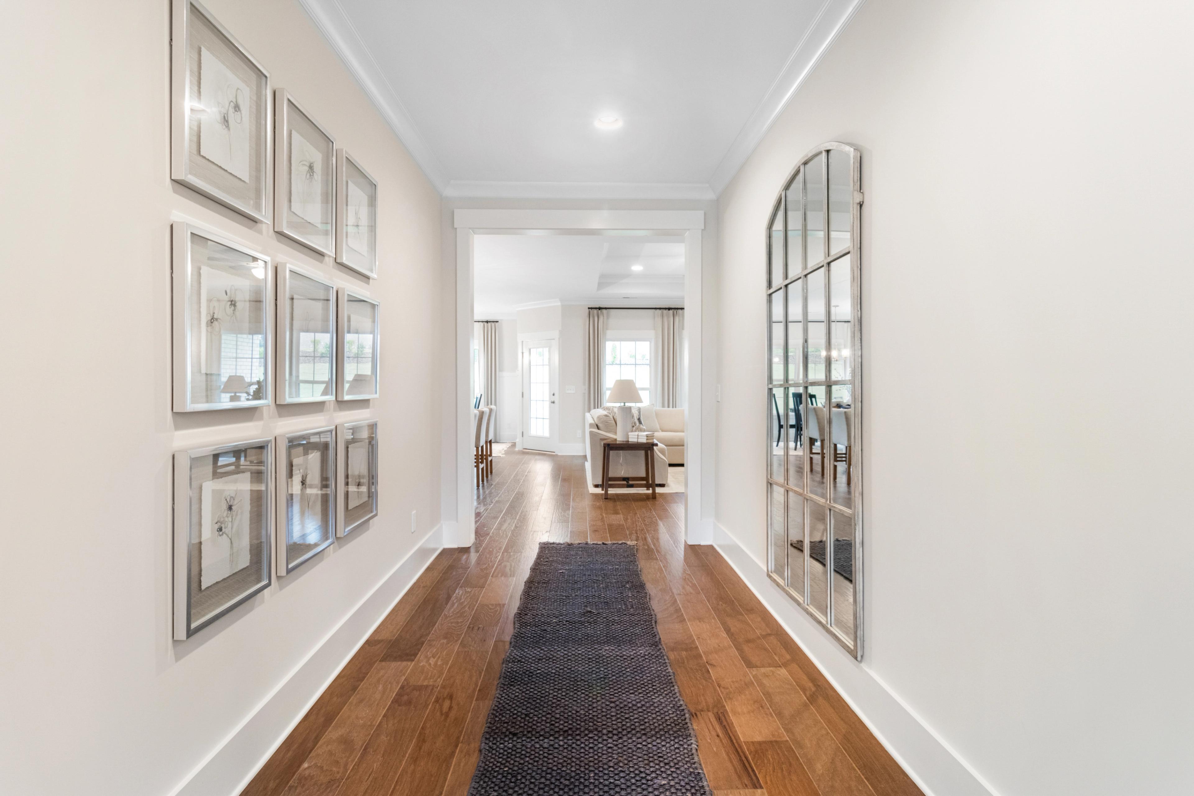 Elegant foyer hallway in Noble Ridge Cullman AL home by Davidson Homes with hardwood floors arched mirror and framed art