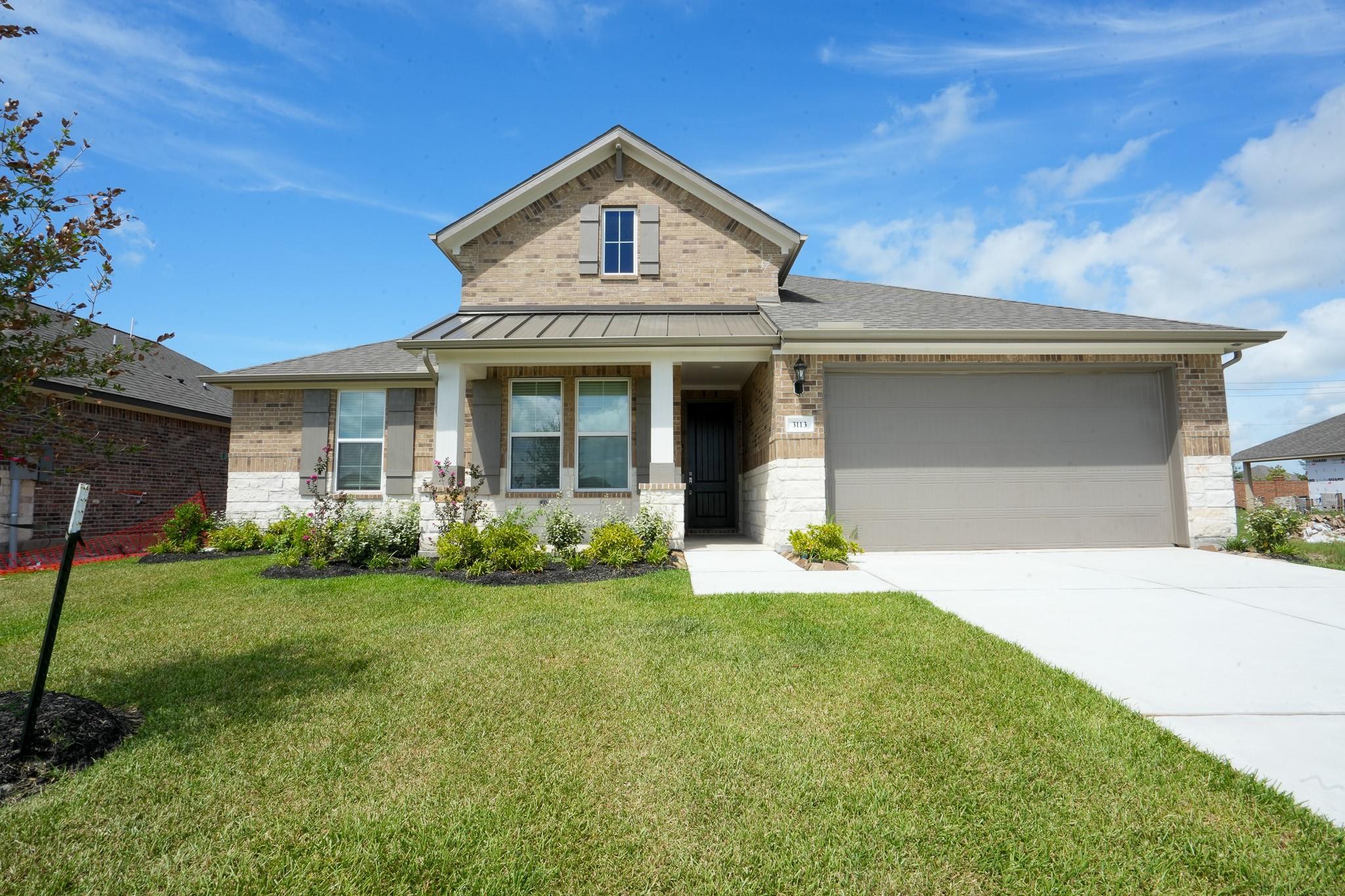 Brick single-story home with 2-car garage, stone accents, and lush green lawn in Lago Mar, Texas City - Davidson Homes Edward C