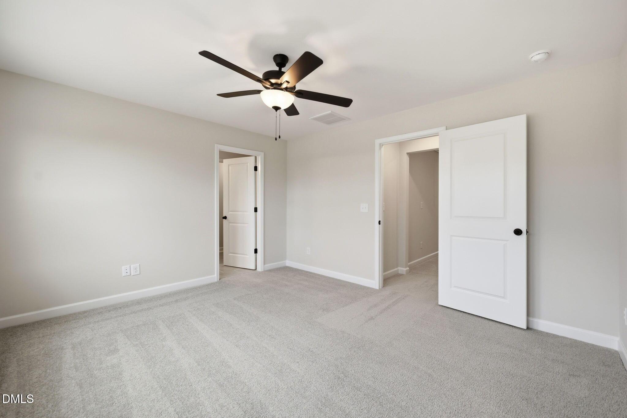 Spacious carpeted bedroom with ceiling fan in The Mitchell floor plan at Camden Park, Knightdale, North Carolina.