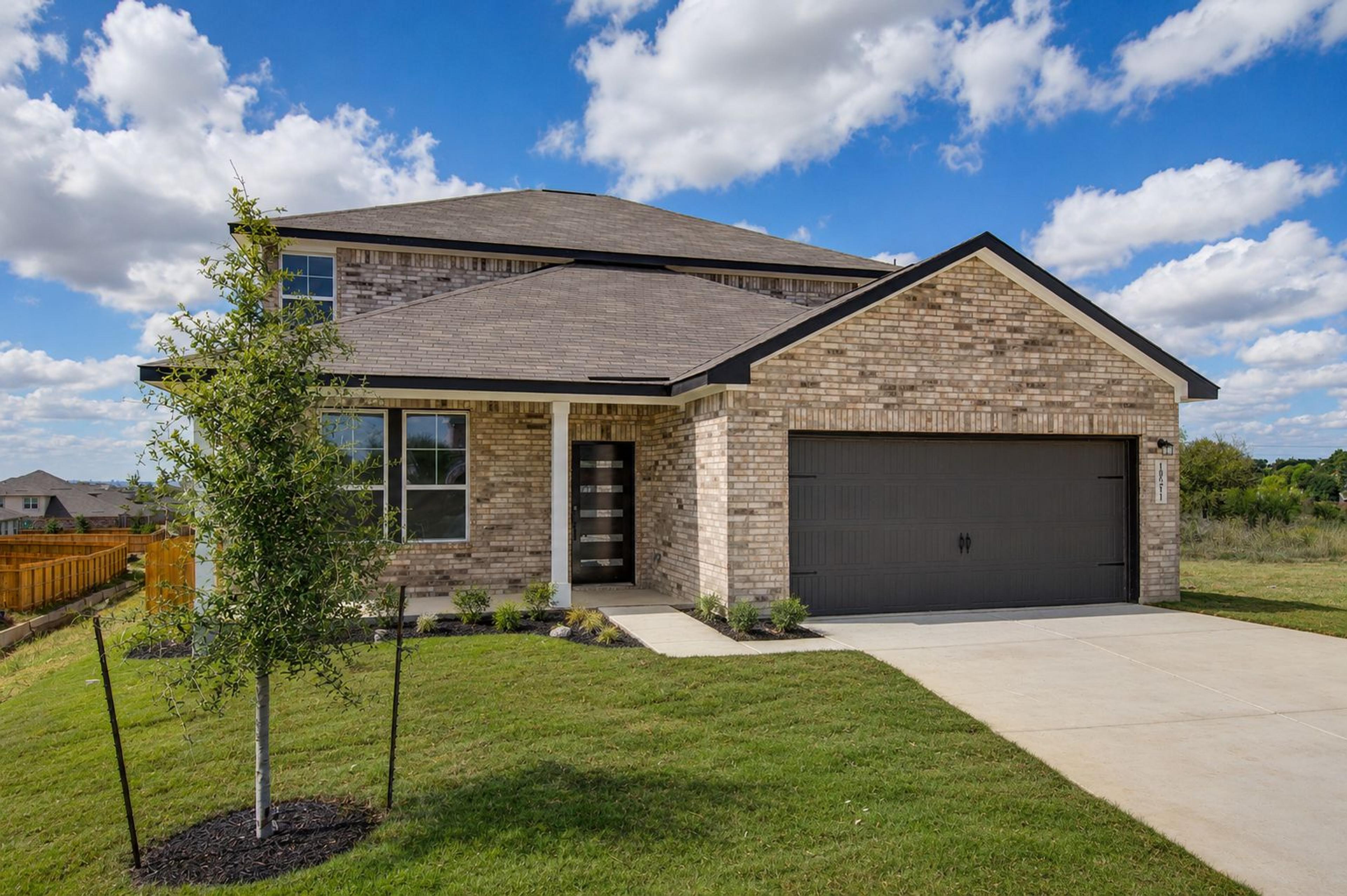 Spacious modern kitchen at Hickory Ridge in Elmendorf TX featuring navy cabinets, quartz counters, stainless appliances, and wood floors