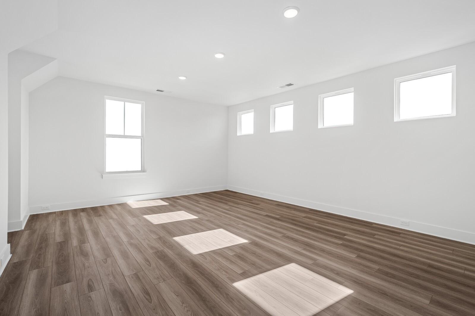 Spacious empty upstairs bedroom with hardwood floors, white walls, and large windows in Davidson Homes The Alston A, Murfreesboro, TN