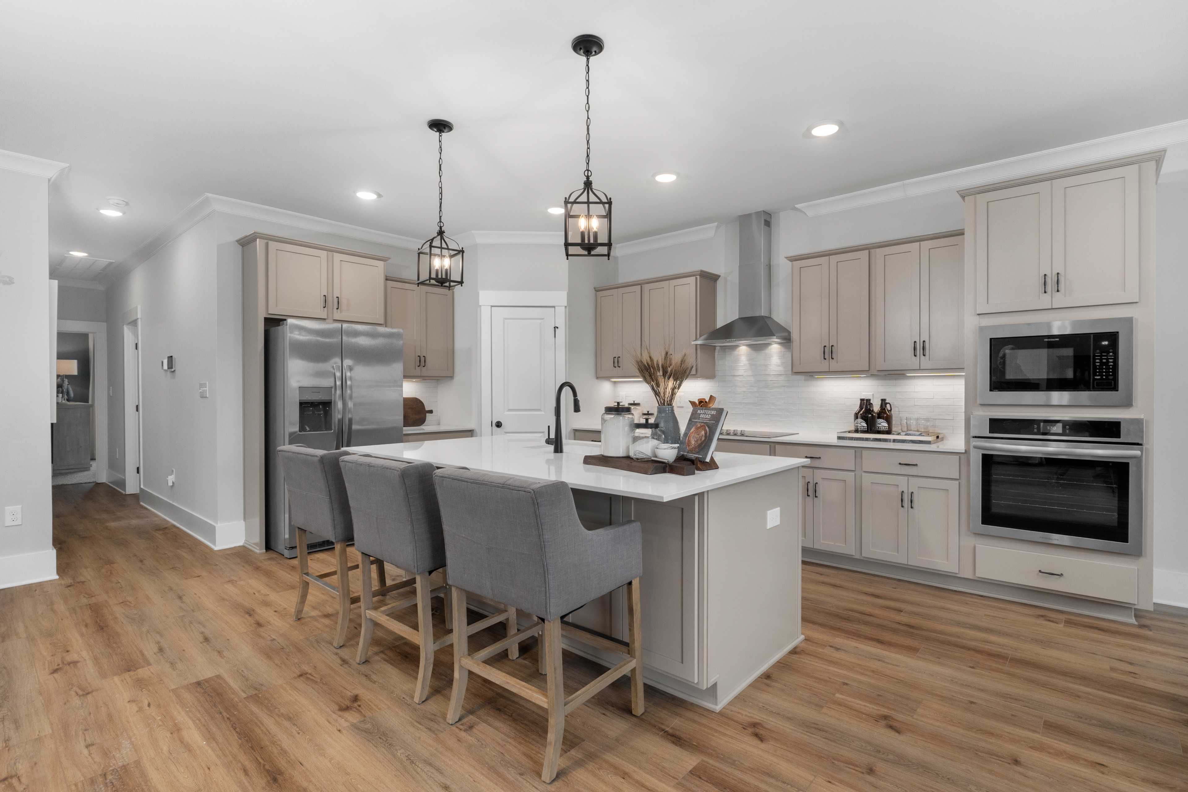 Spacious modern kitchen at Kendall Farms in Toney, Alabama with quartz island, bar seating, stainless appliances, and hardwood floors