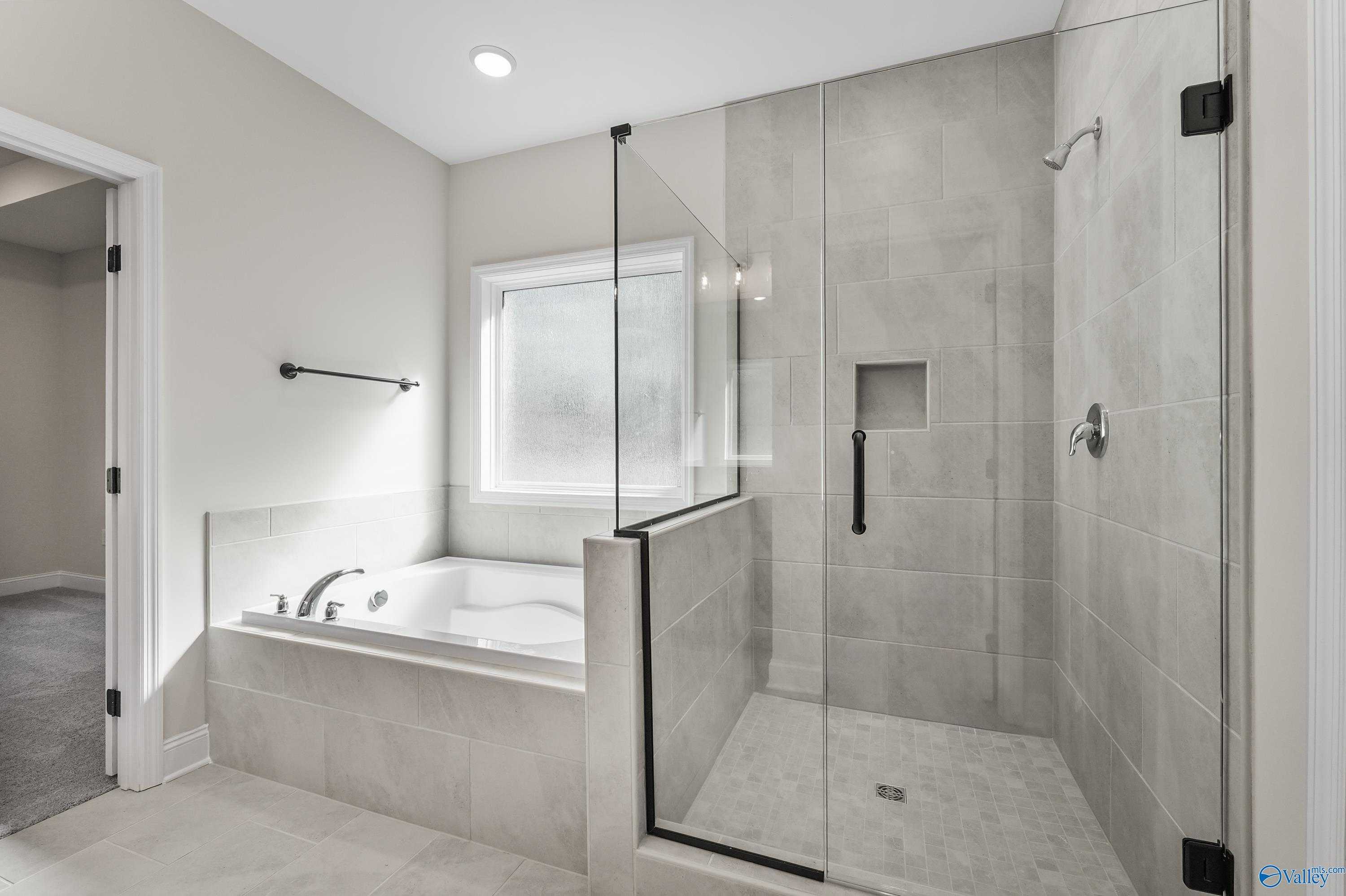 Modern master bathroom with soaking tub, glass shower enclosure, and tiled walls in Davidson Homes The Montgomery C, Decatur, AL