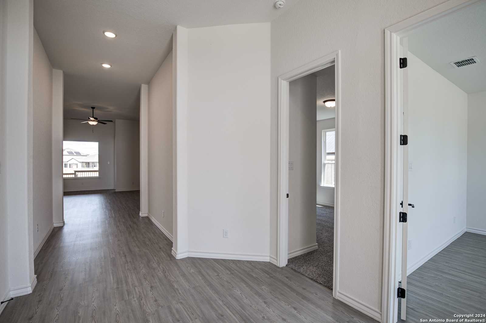 Spacious hallway with gray luxury vinyl plank flooring, recessed lights, and ceiling fan in Davidson Homes The Garner B, Castroville, Texas