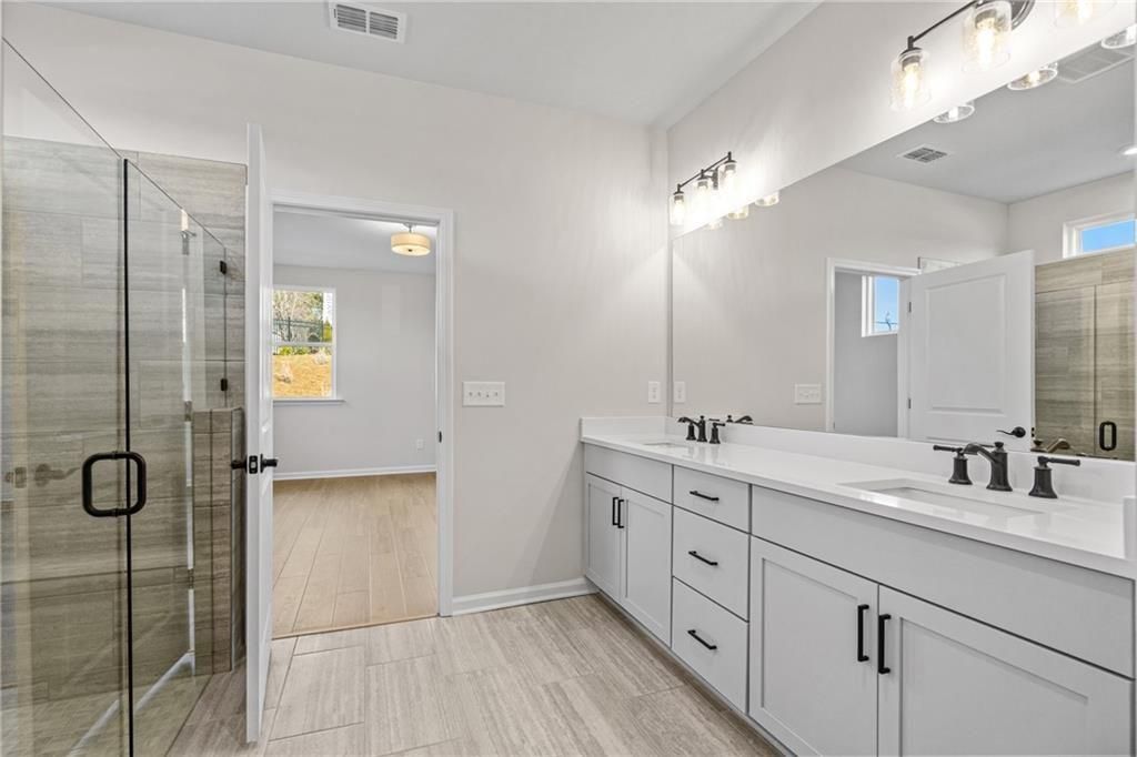 Modern master bathroom featuring frameless glass shower, double vanity with white quartz, and luxury finishes in Davidson Homes The Edison A, Loganville, GA