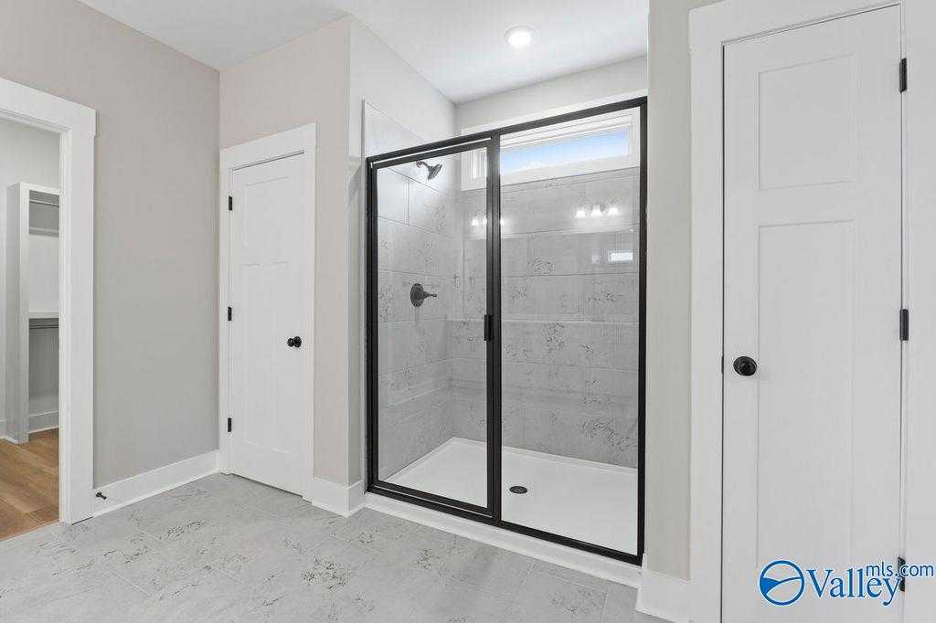 Modern master bathroom with large framed glass shower, subway tile, and light gray walls in Evermore Homes The Oxford, Owens Cross Roads, Alabama
