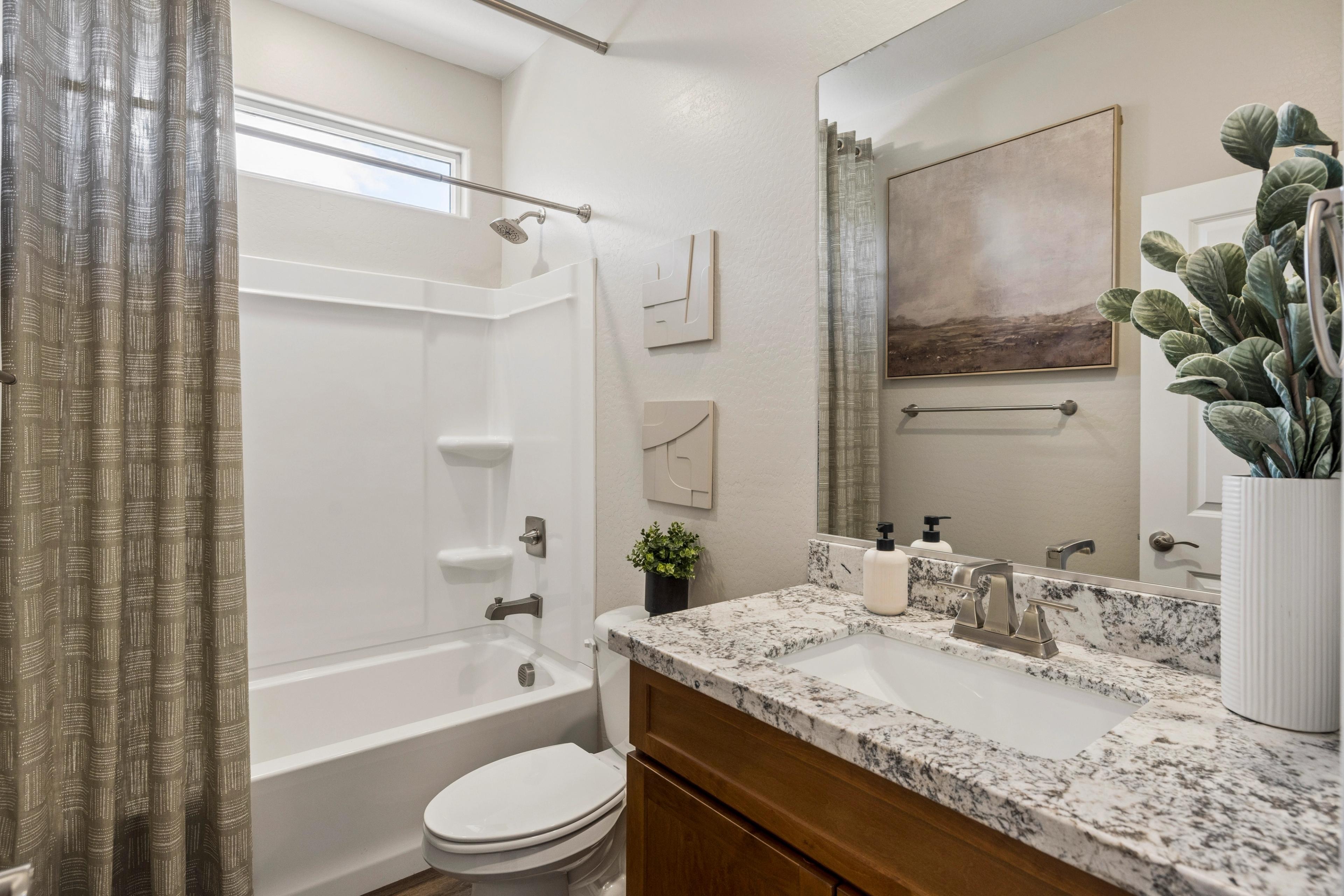 Elegant bathroom at Senator Cottages in Prescott Arizona with bathtub-shower combo, quartz vanity, and modern decor