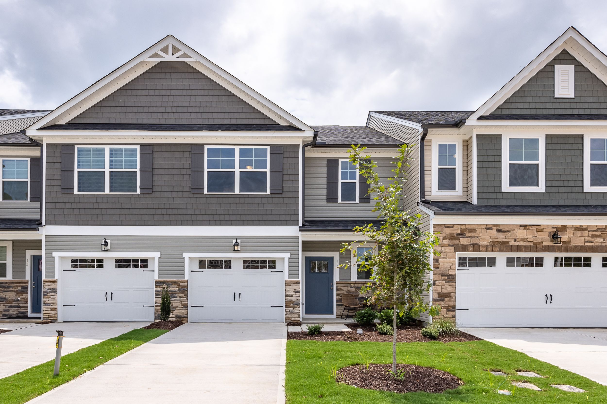 Two-story multi-family exterior of The Warren by Davidson Homes in Lillington, NC, featuring stone accents and garage.