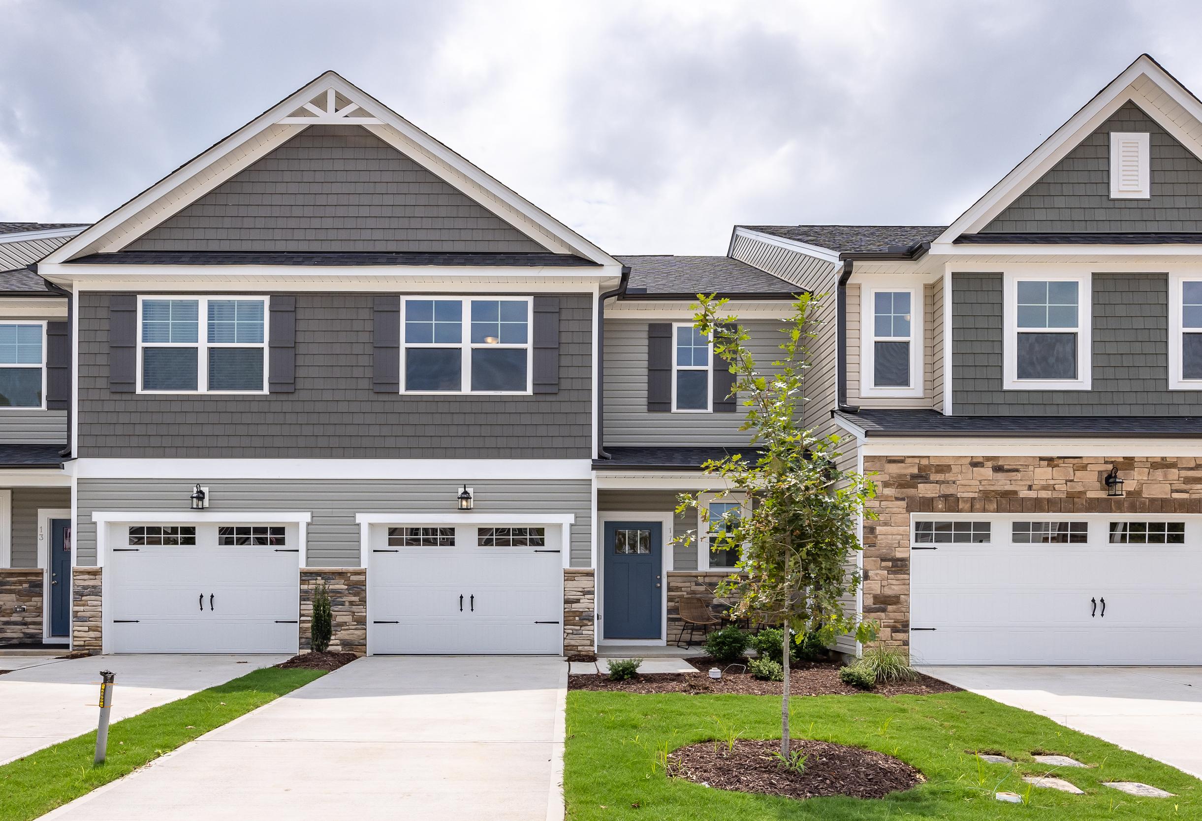 Two-story multi-family exterior of The Warren by Davidson Homes in Lillington, NC, featuring stone accents and garage.