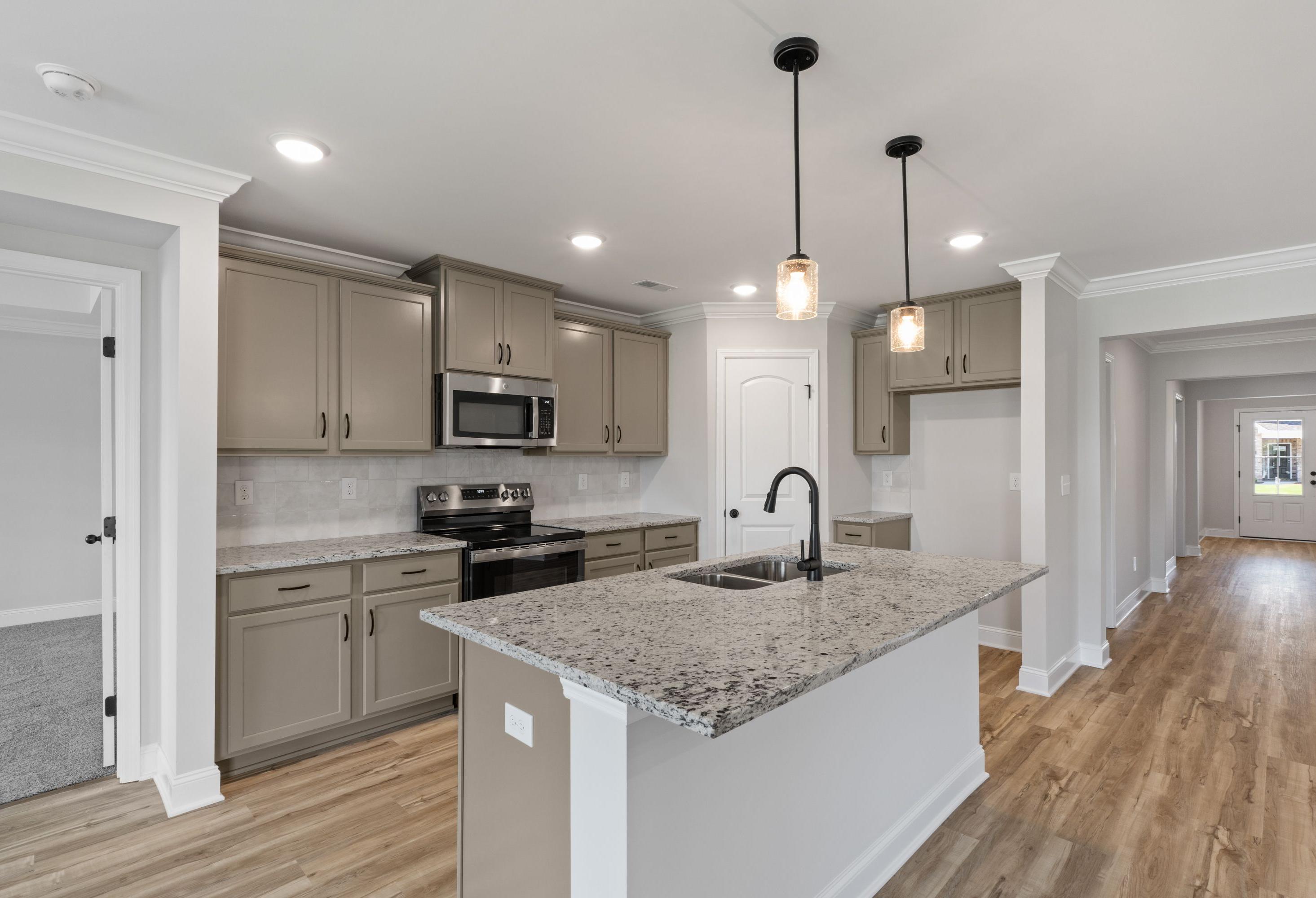 Modern kitchen in The Holly C featuring granite countertops, a central island, and stylish cabinetry in Heartland, Texas.