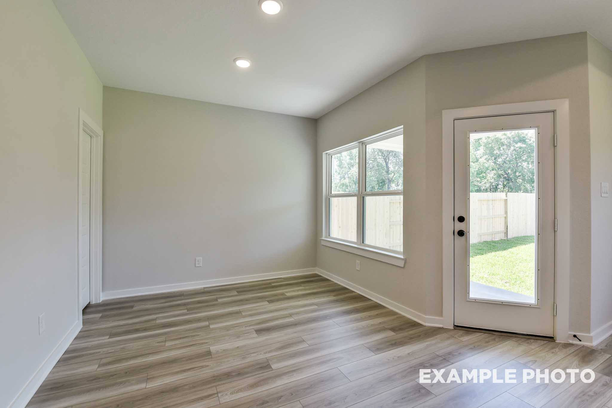 Bright open living room in The Daphne G with large windows, sliding glass door to backyard, hardwood floors, Crosby TX home