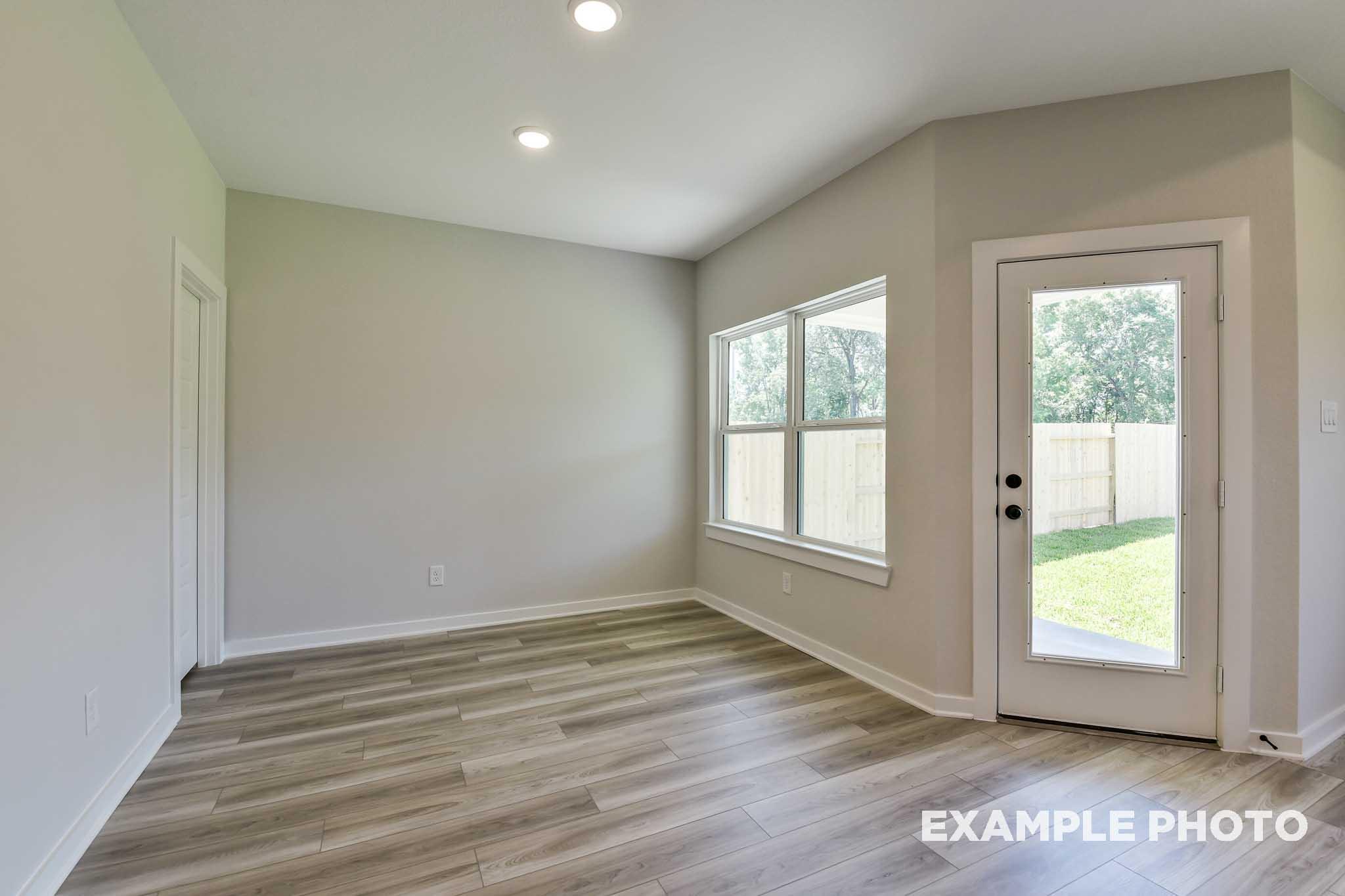 Bright open living room in The Daphne G with large windows, sliding glass door to backyard, hardwood floors, Crosby TX home