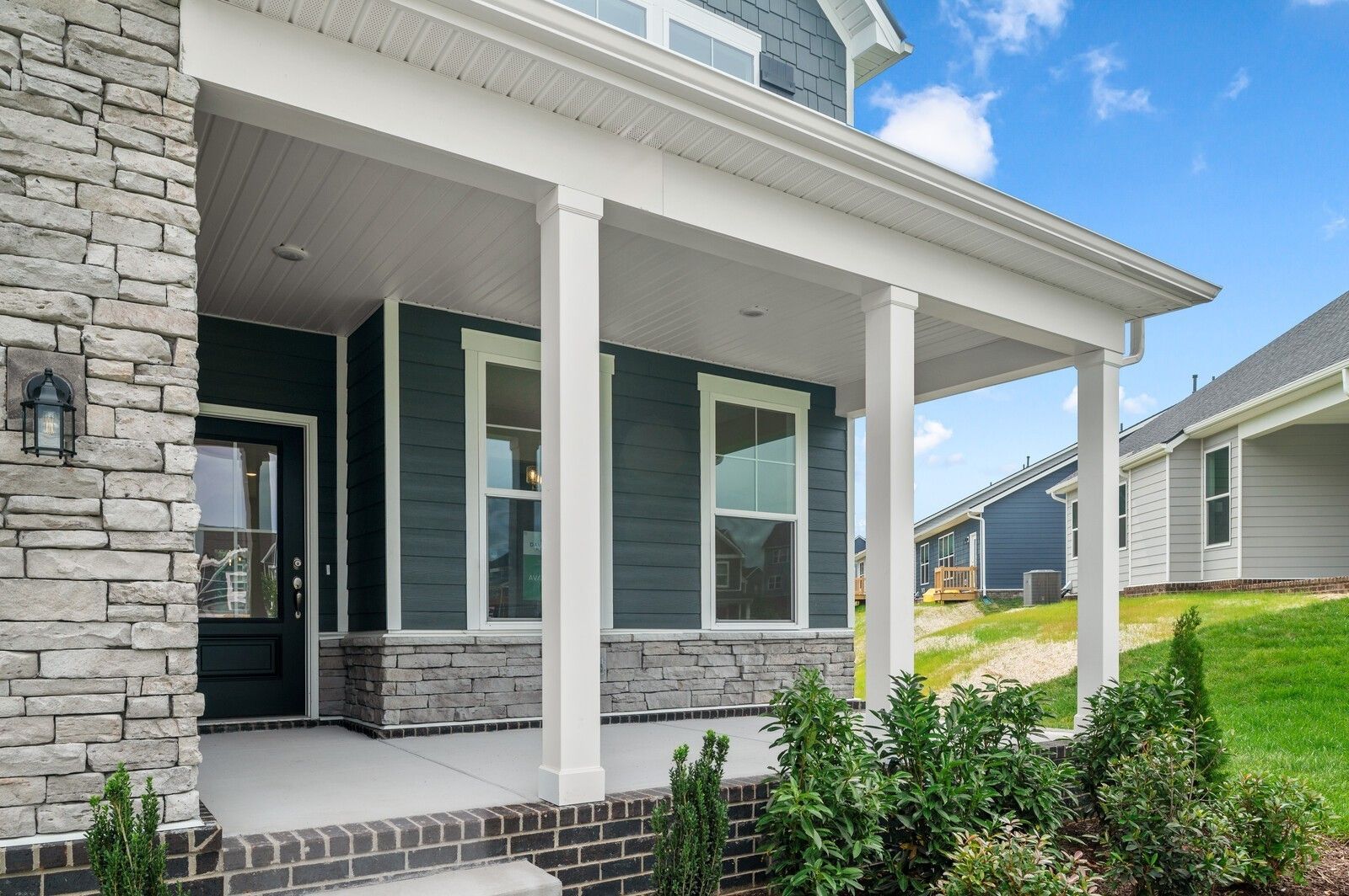 Covered front porch with stone accents on a Willow floor plan home by Davidson Homes in Calista Farms, White House, Tennessee.