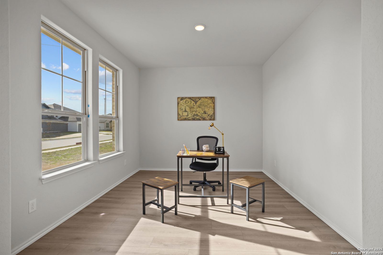 Modern home office with metal desk, ergonomic chair, stools, and large windows in Davidson Homes The Douglas C, Seguin, Texas
