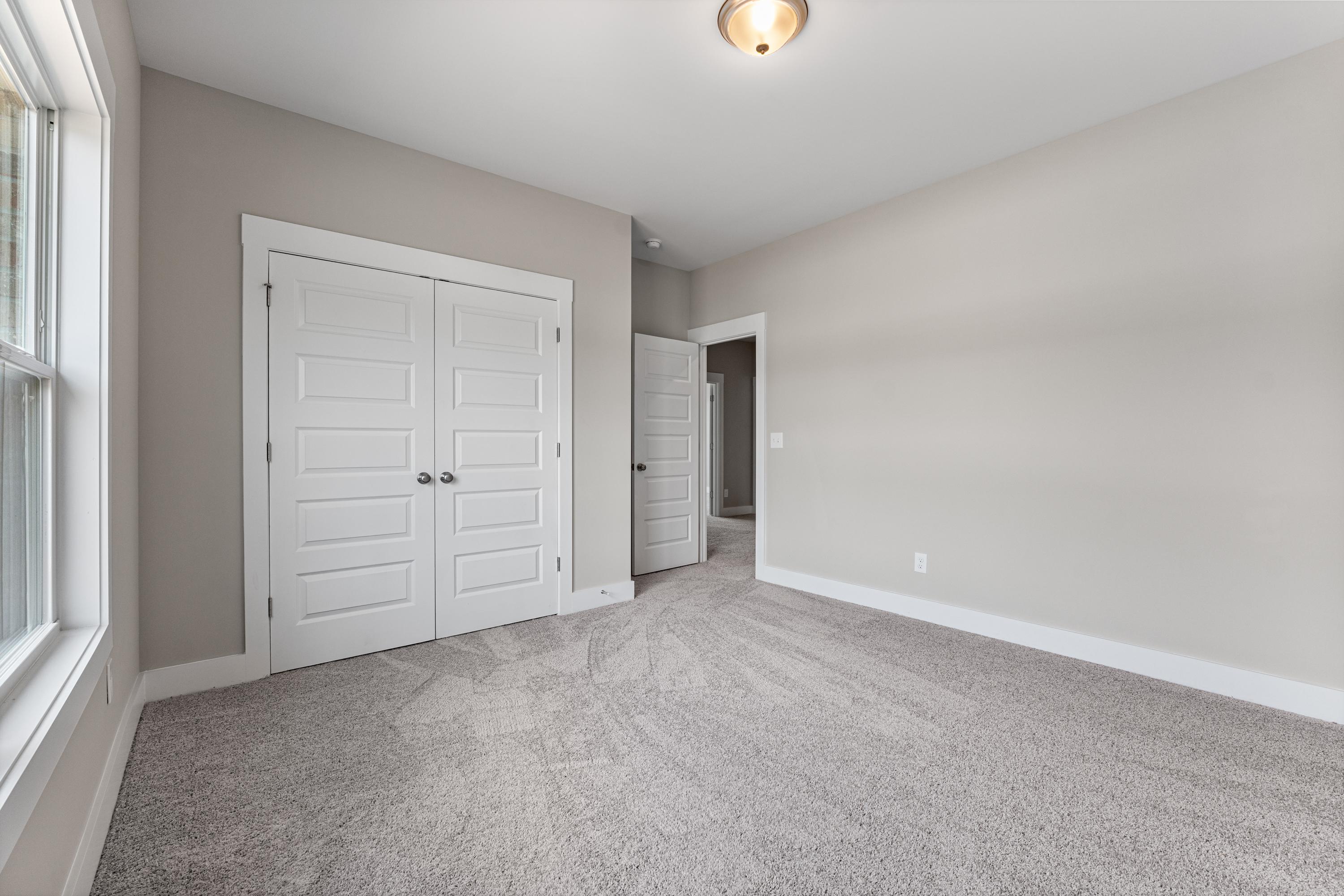 Spacious master bedroom in The Oxford C with gray walls, plush carpet, double closet doors, and en-suite bath access