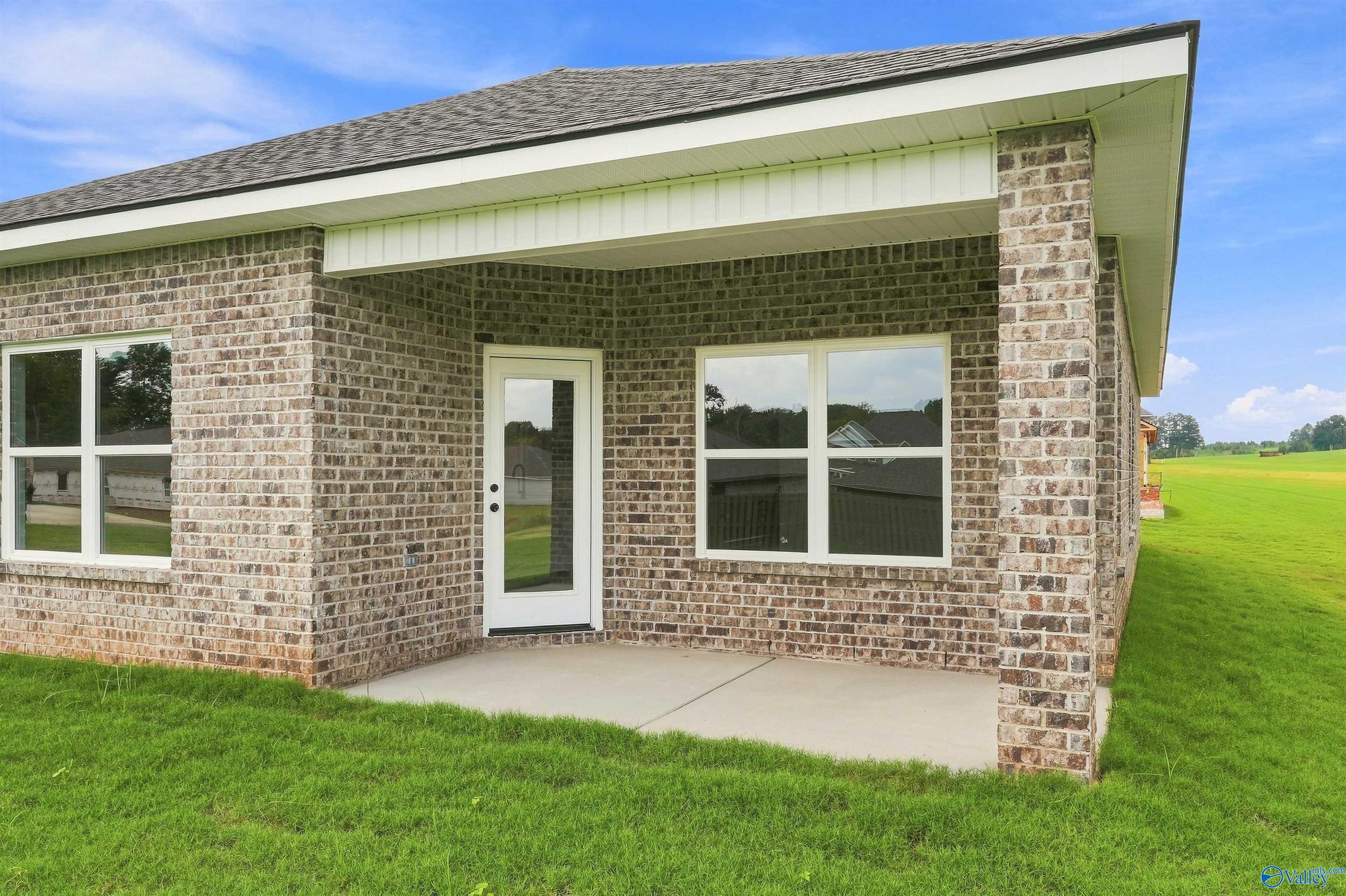 Covered brick patio with white door overlooking green backyard of Davidson Homes Franklin C plan in The Meadows, Athens, Alabama