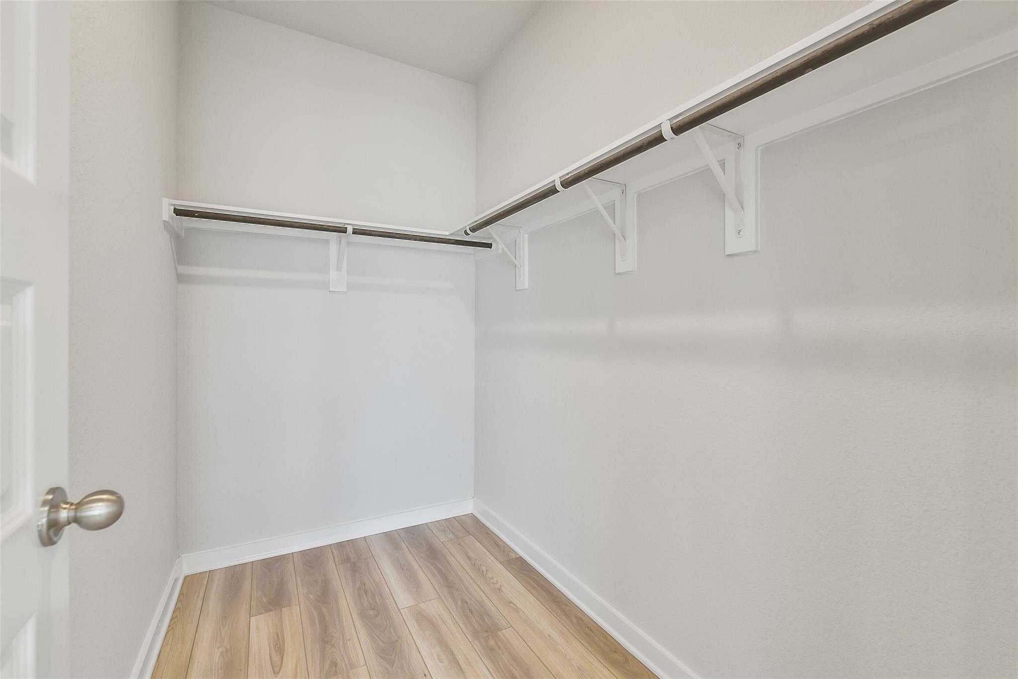 Spacious walk-in closet with white walls, wood flooring, and built-in shelving in Davidson Homes The Rio Grande H, Magnolia, TX