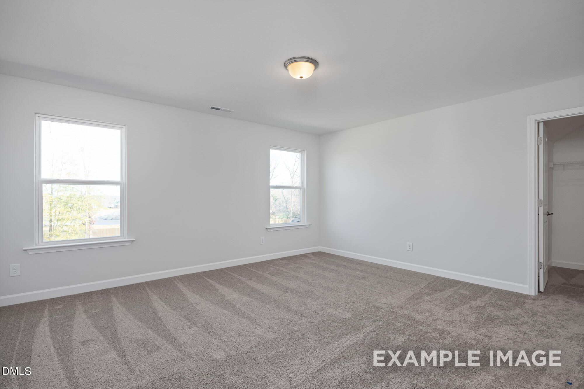 Bright secondary bedroom with white walls, large windows, and walk-in closet in Davidson Homes The Cypress B II, Angier, NC