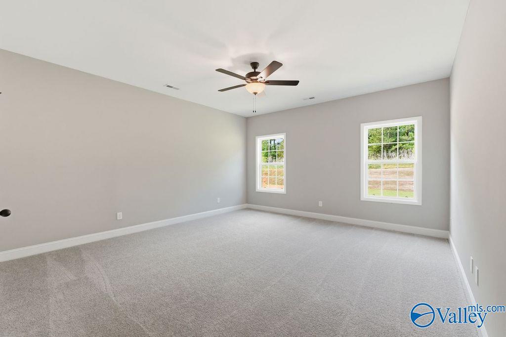 Spacious, neutrally painted bedroom with plush carpet and ceiling fan in The Rockford floor plan, Cain Park, Hartselle.