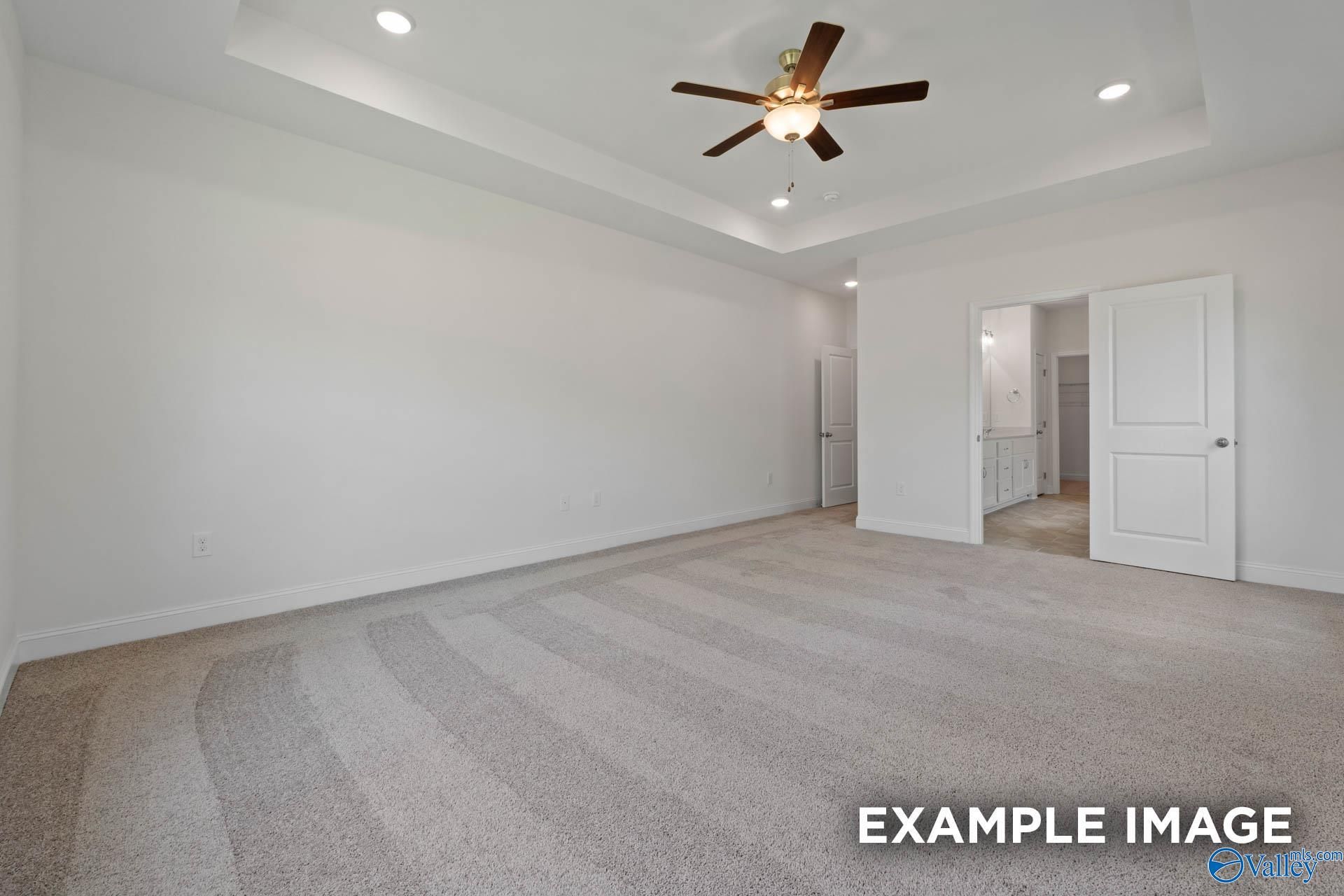 Spacious bedroom with tray ceiling, ceiling fan, and en-suite bathroom in Davidson Homes The Oxford, Huntsville, Alabama
