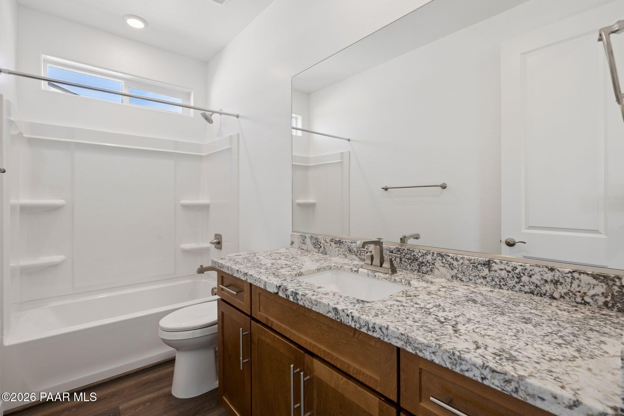 Modern bathroom featuring granite vanity, white tiled shower, bathtub combo in Davidson Homes The Monarch A, Prescott, AZ