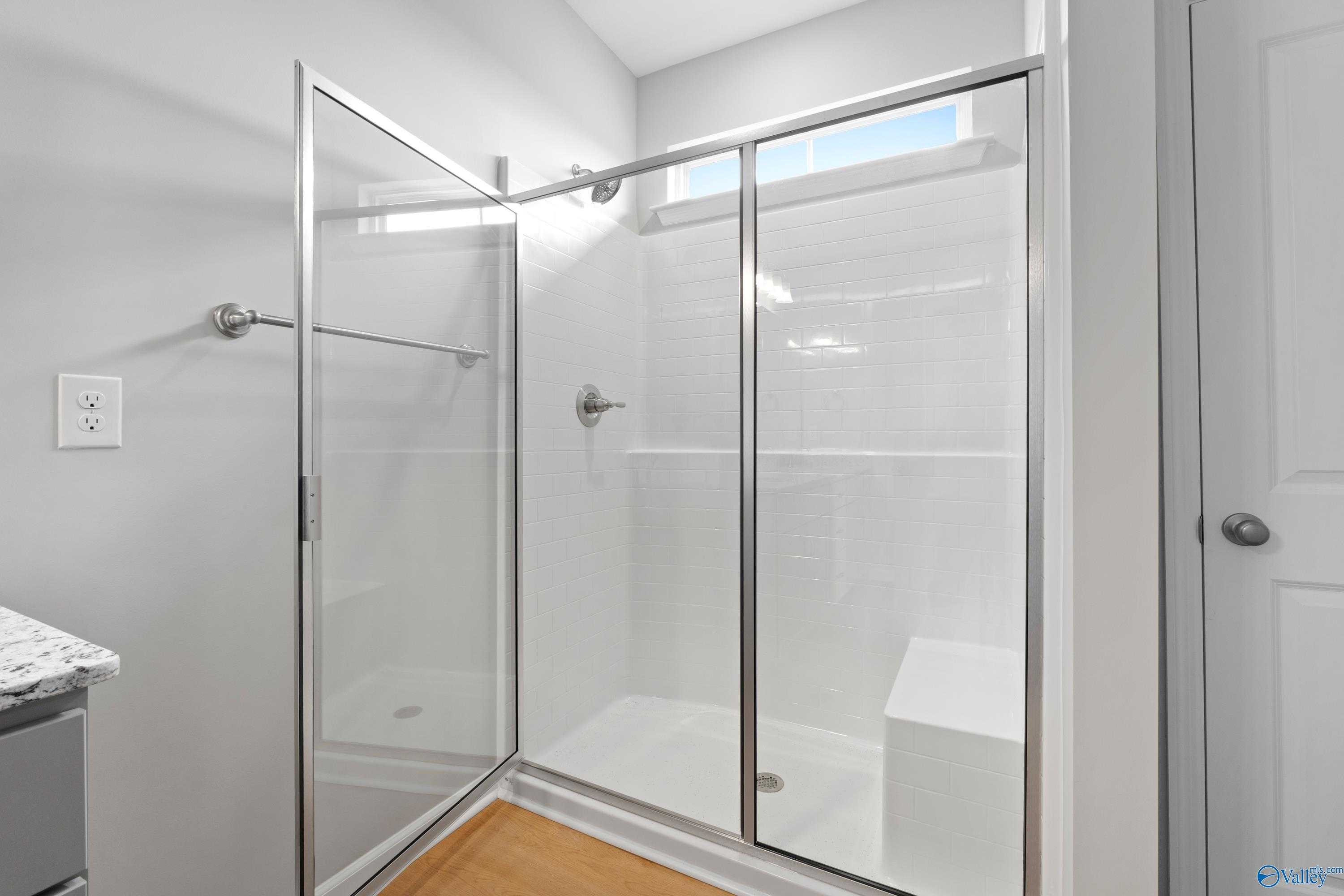 Modern walk-in shower with frameless glass enclosure, subway tiles, and built-in bench in Davidson Homes The Orion bathroom, Athens, Alabama