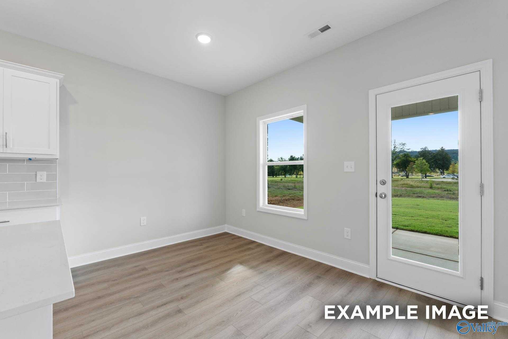 Bright utility room with white cabinets, subway tile backsplash, and glass door to green backyard in Davidson Homes The Butler, Huntsville AL