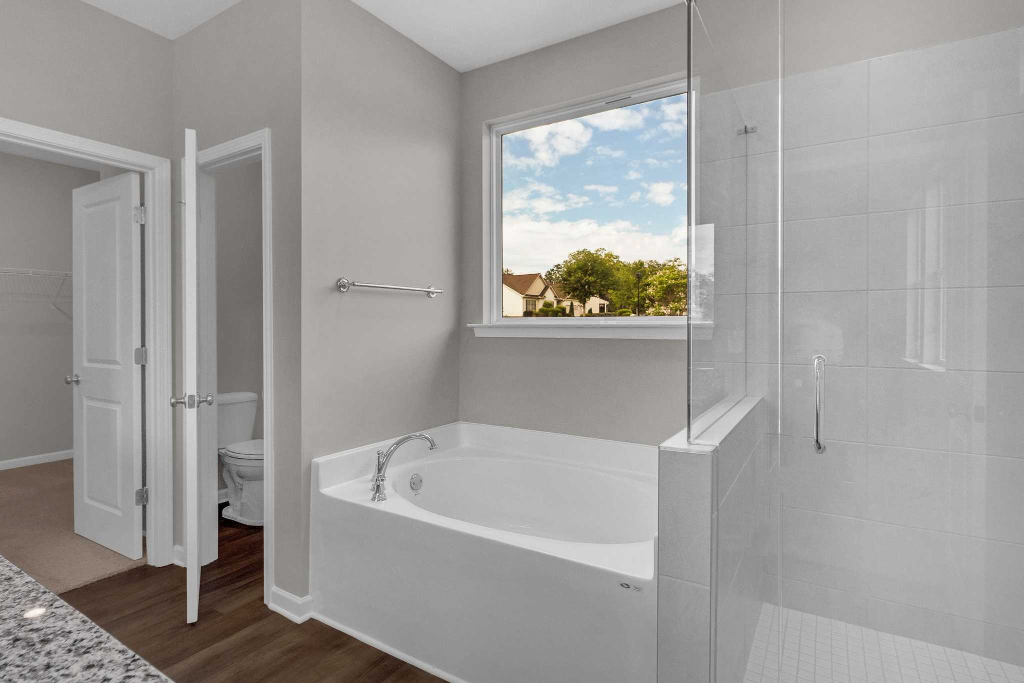 Spacious master bathroom at Ivy Glen in Perry Georgia with freestanding tub, glass shower, and scenic window view