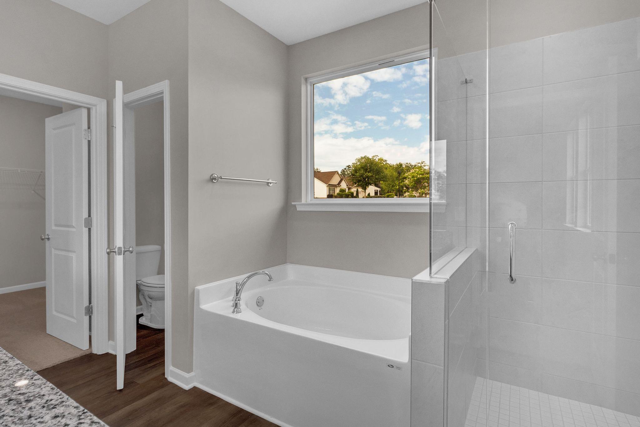 Spacious master bathroom at Ivy Glen in Perry Georgia with freestanding tub, glass shower, and scenic window view