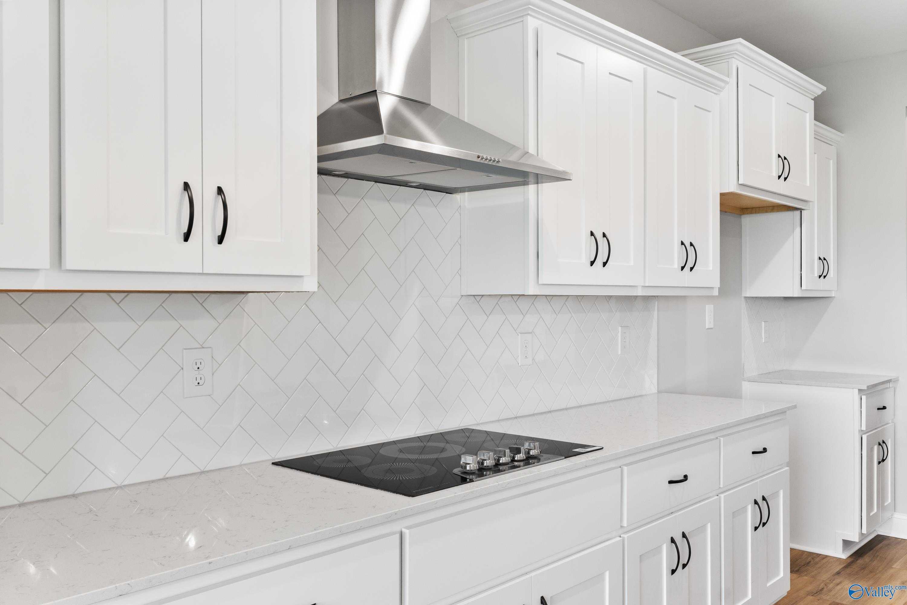 Modern white shaker kitchen with subway tile backsplash, stainless steel hood, and 5-burner cooktop in Davidson Homes The Finleigh, Toney, AL