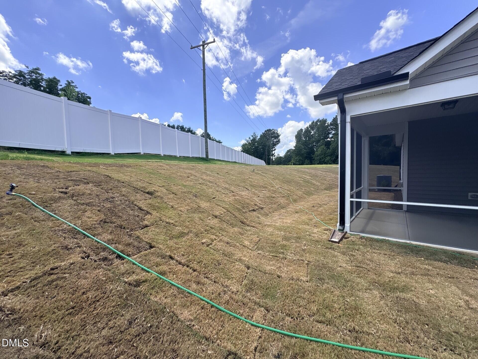 Screened-in porch overlooking a grassy backyard with a white privacy fence at The Ash C home in Woodland Crossing, Zebulon.