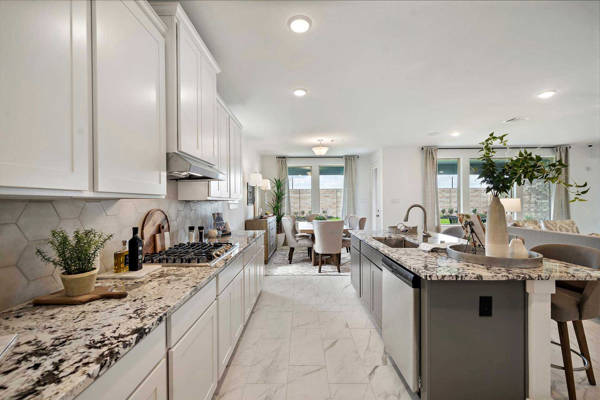 Spacious open-concept kitchen in Sierra Vista Rosharon TX with white cabinets, granite island, gas range and adjacent dining area