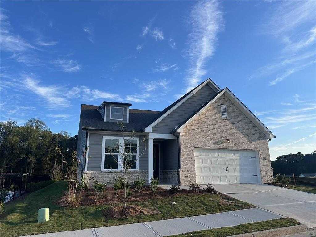 Modern gray brick 1-story home with gabled roof, large windows, 2-car garage, and landscaped yard in Kelly Preserve, Loganville, Georgia