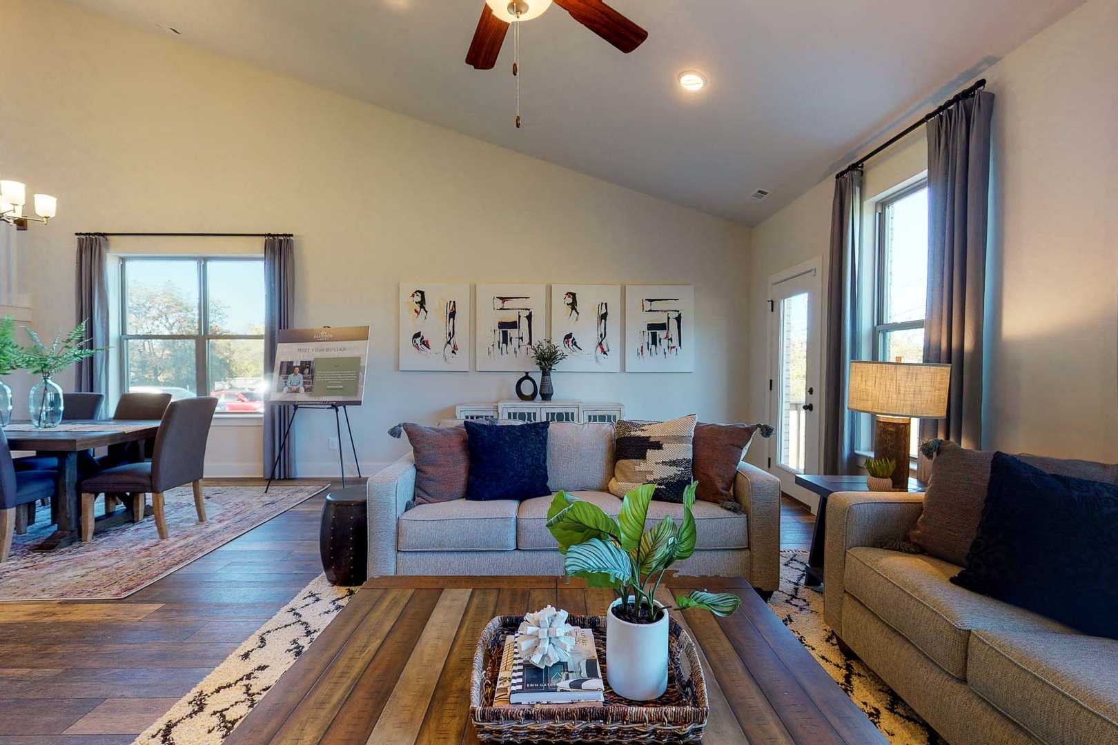 Open-concept living and dining room at Liberty Creek in Gallatin TN with hardwood floors ceiling fan modern sofas and artwork