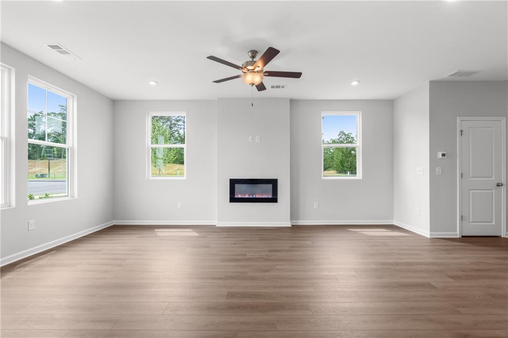 Spacious living room with gas fireplace, ceiling fan, large windows, hardwood floors in Davidson Homes The Monroe B, Emerson, Georgia