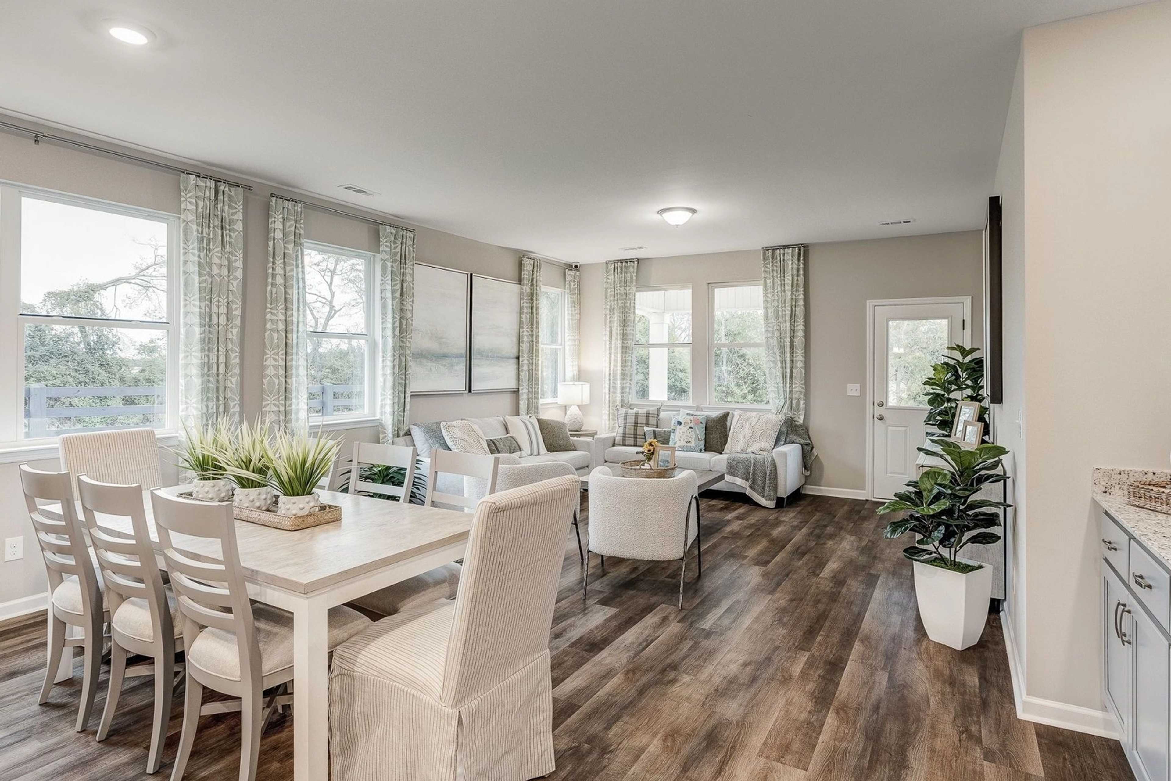 Spacious open-concept living and dining area at Carroll Green in Harvest AL with hardwood floors, neutral tones, and large windows