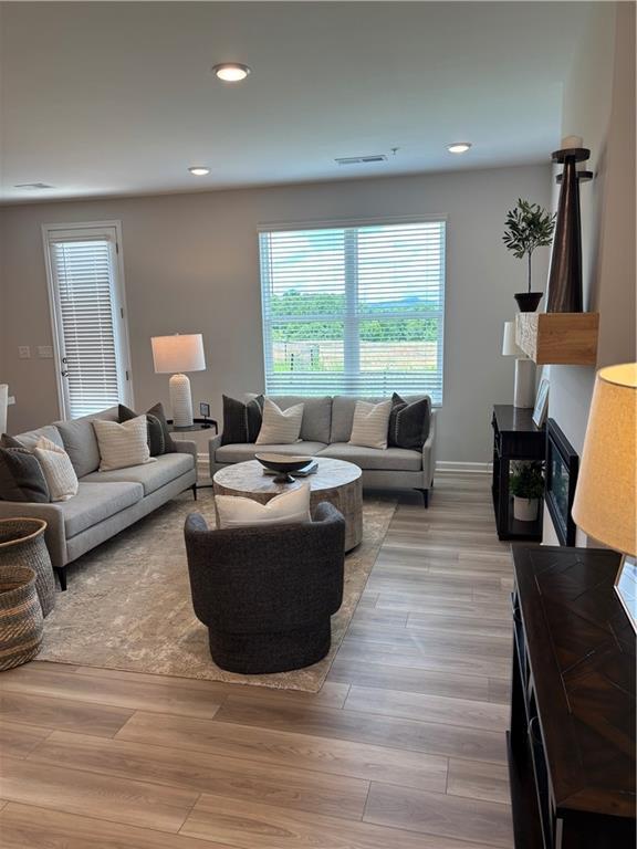 Modern open living room with light wood flooring and fireplace in The Wake F floor plan, Hemingway, Cumming, Georgia.
