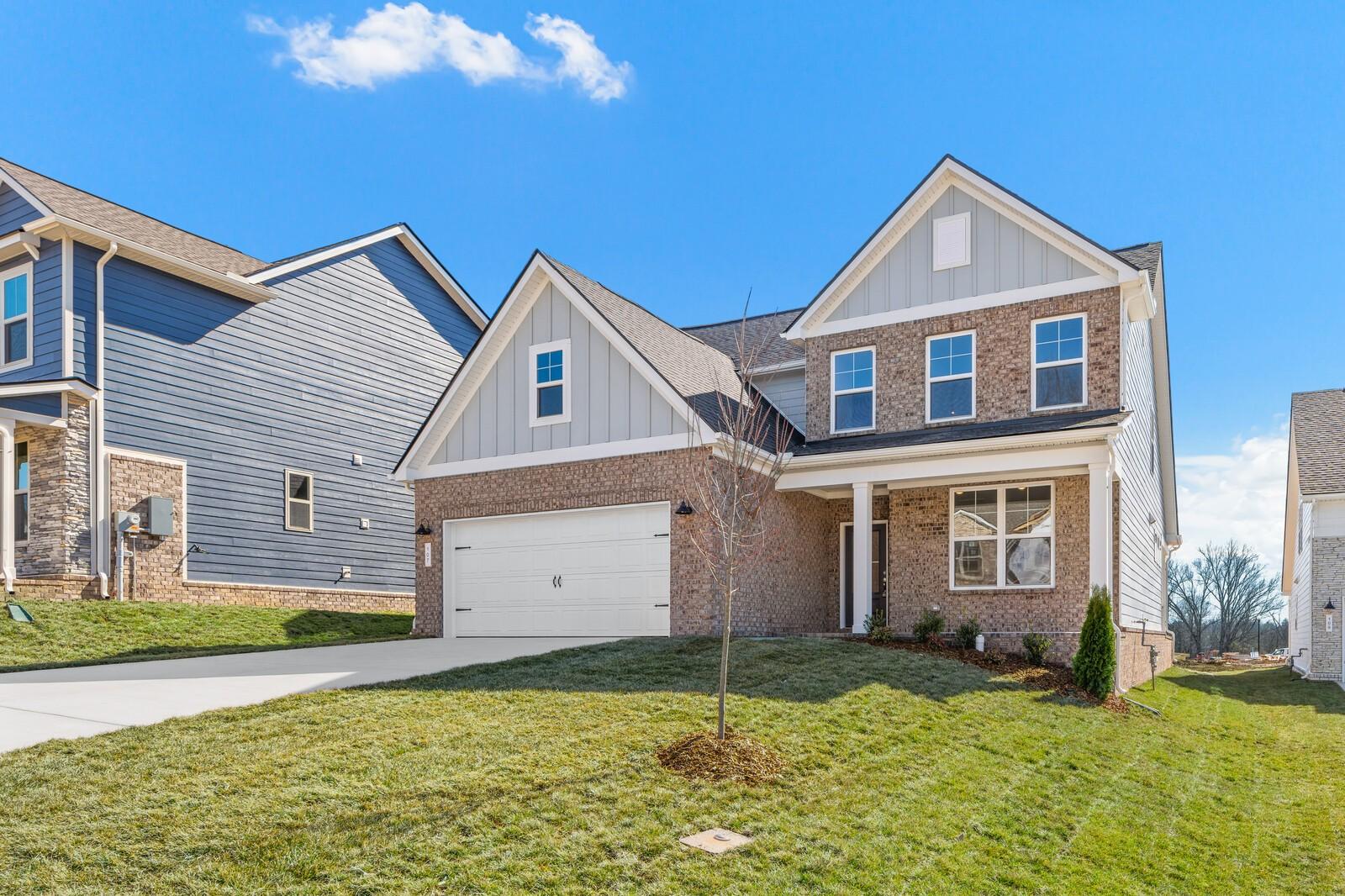 Two-story brick home with 2-car garage, front porch, and manicured lawn in Woods Crossing, Gallatin, Tennessee by Davidson Homes The Ash A