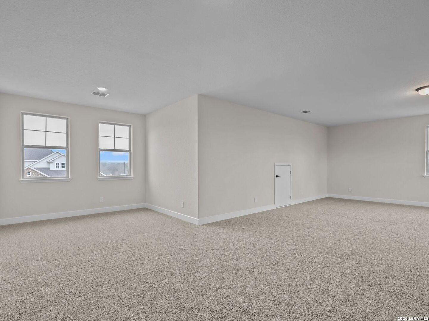 Spacious carpeted game room or second-story living area in The Belmont H floor plan at Potranco Oaks, Castroville, Texas.