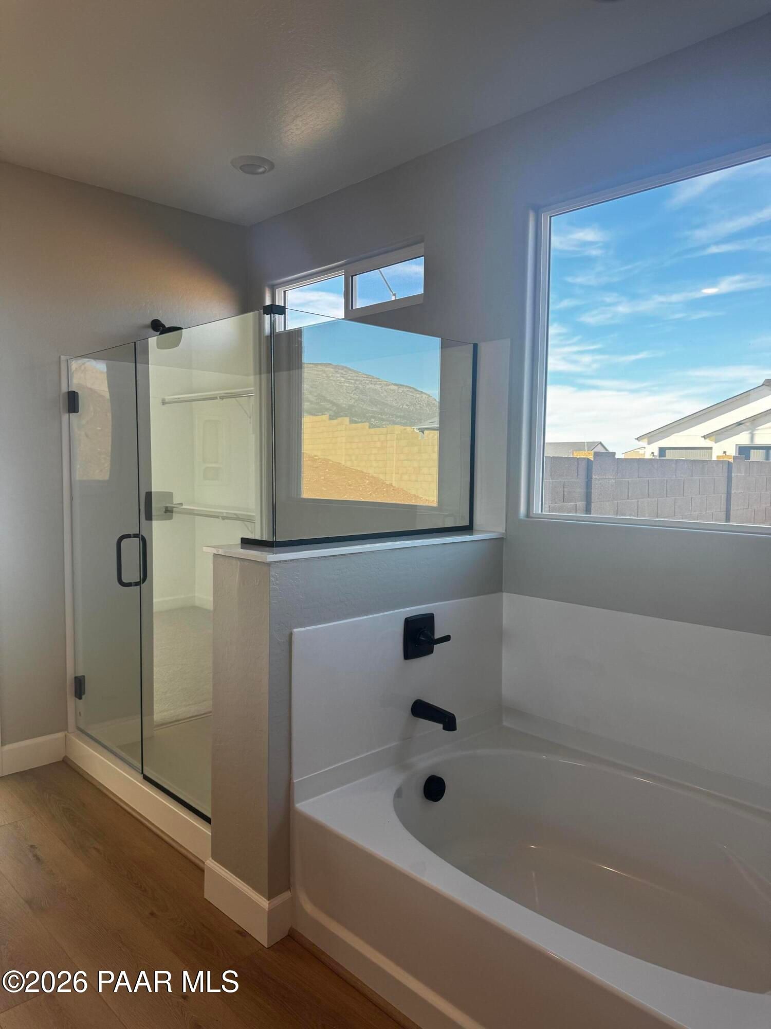 Modern master bathroom with frameless glass shower, soaking tub, and mountain-view window in Evermore Homes The Monarch B, Prescott Valley