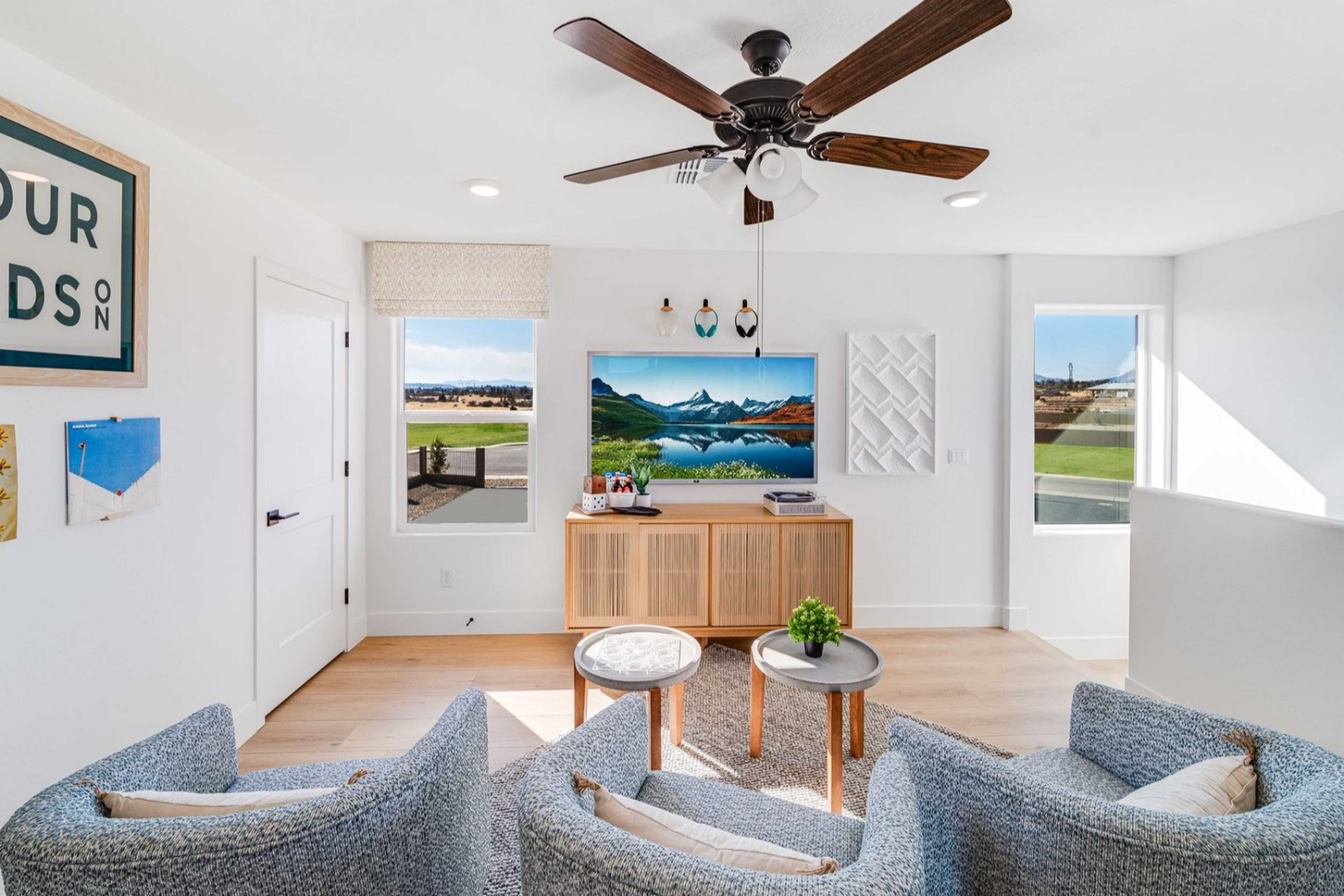Cozy upstairs loft in The Wilmington home design featuring gray armchairs, wooden tables, TV, and scenic Arizona views