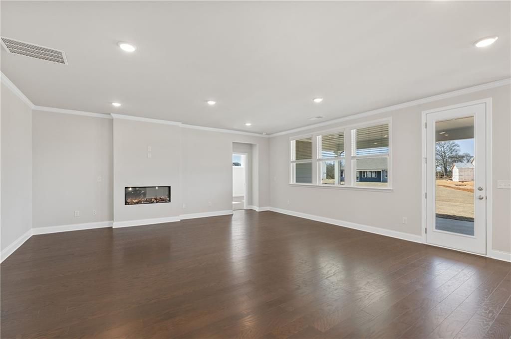 Open-concept great room with hardwood floors, linear fireplace, and glass-panel door in Davidson Homes Harrison G plan, Winder GA