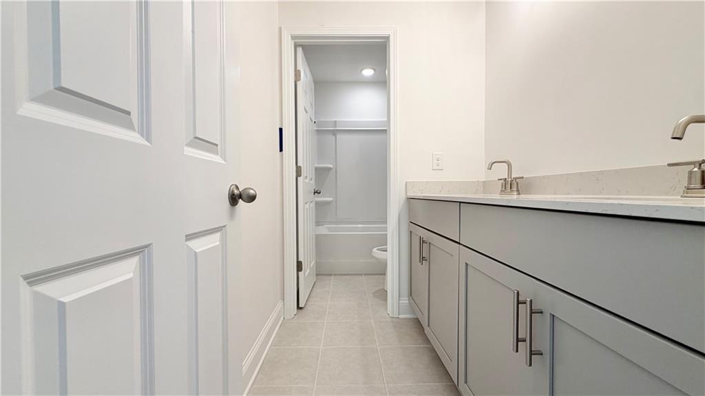 Modern bathroom with double vanity and tiled floor in The Hickory C floor plan at Wehunt Meadows, Hoschton, Georgia.