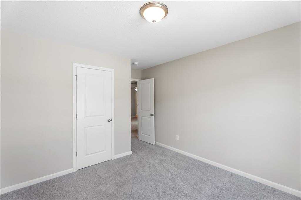 Secondary bedroom featuring beige walls, gray carpet, and adjacent bath door in Davidson Homes The Washington, Phenix City