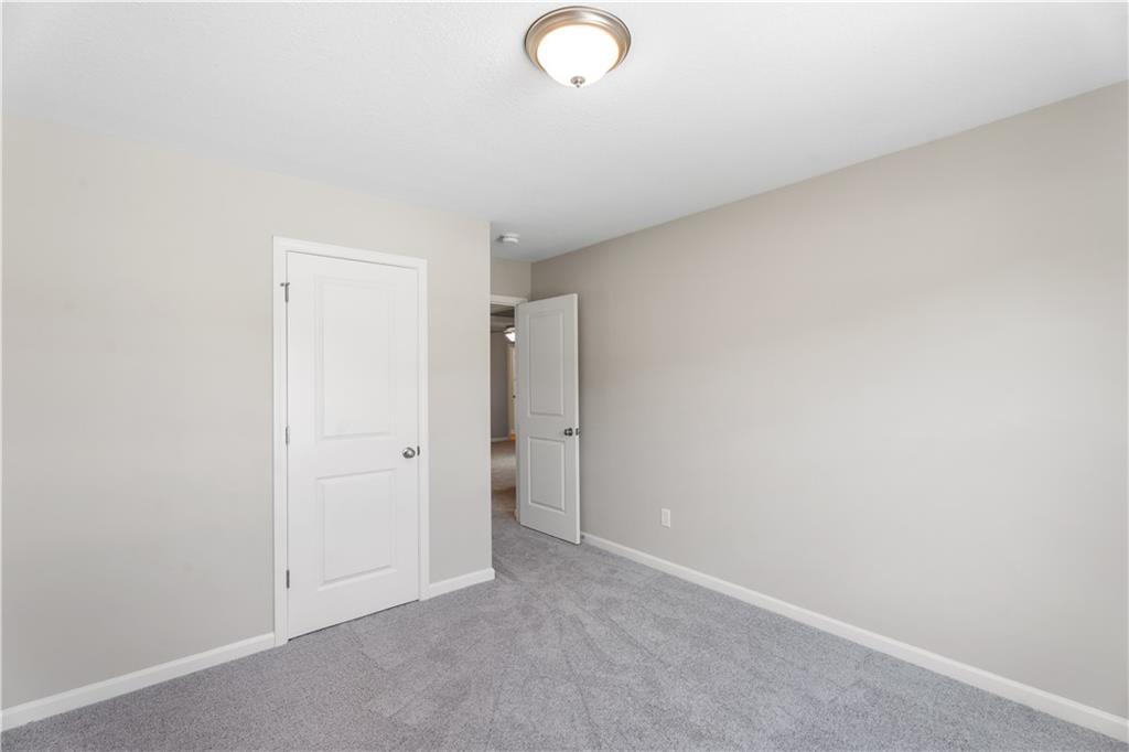 Secondary bedroom featuring beige walls, gray carpet, and adjacent bath door in Davidson Homes The Washington, Phenix City