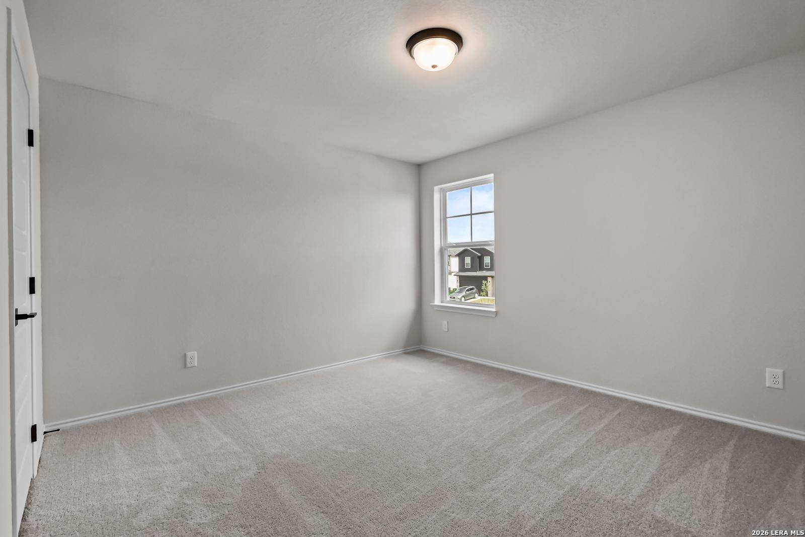 Spacious secondary bedroom with neutral carpet in The Douglas C floor plan by Davidson Homes in Hannah Heights, Seguin, Texas.